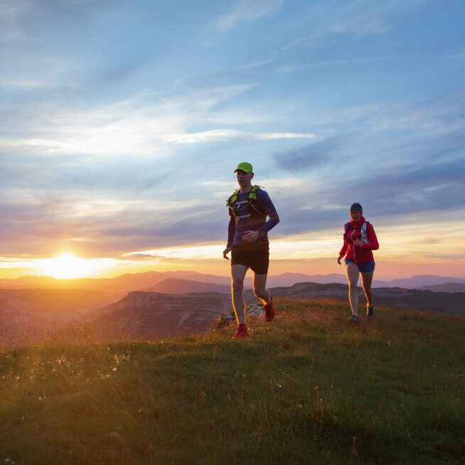 Two athletes trail running in the hills during sunset. Shallow D.O.F. and with motion blur.